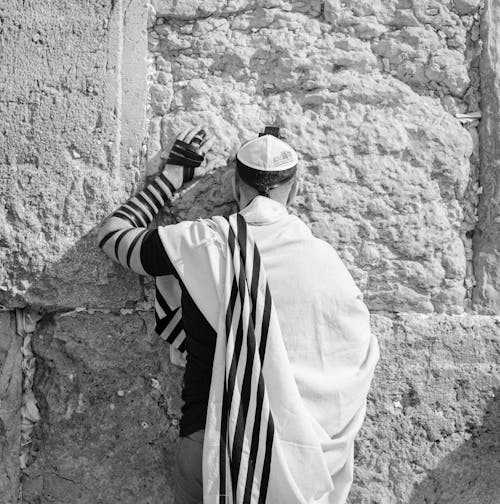 Free Anonymous Jewish man in traditional wear praying near old wall Stock Photo