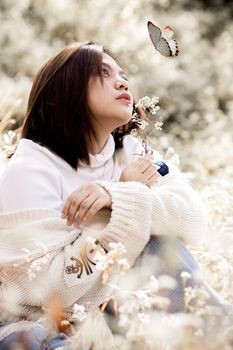 这幅肖像描绘了一位亚洲女性拥抱自然、与蝴蝶互动的和平景象