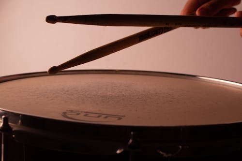 Free Crop musician playing drum using wooden drumsticks Stock Photo