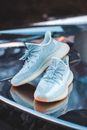 Modern footwear with tied laces and ribbed soles reflecting on metal surface
