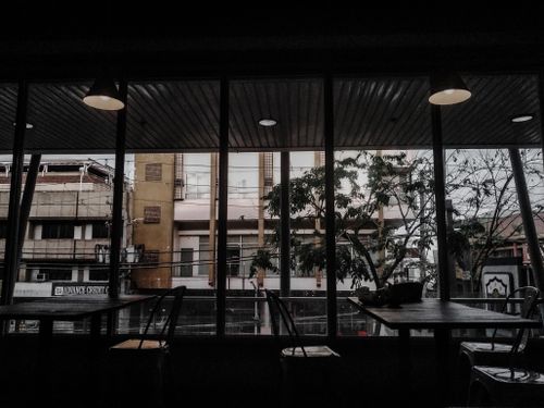 Free Cozy cafe interior with tables and chairs overlooking an urban street through large windows. Stock Photo
