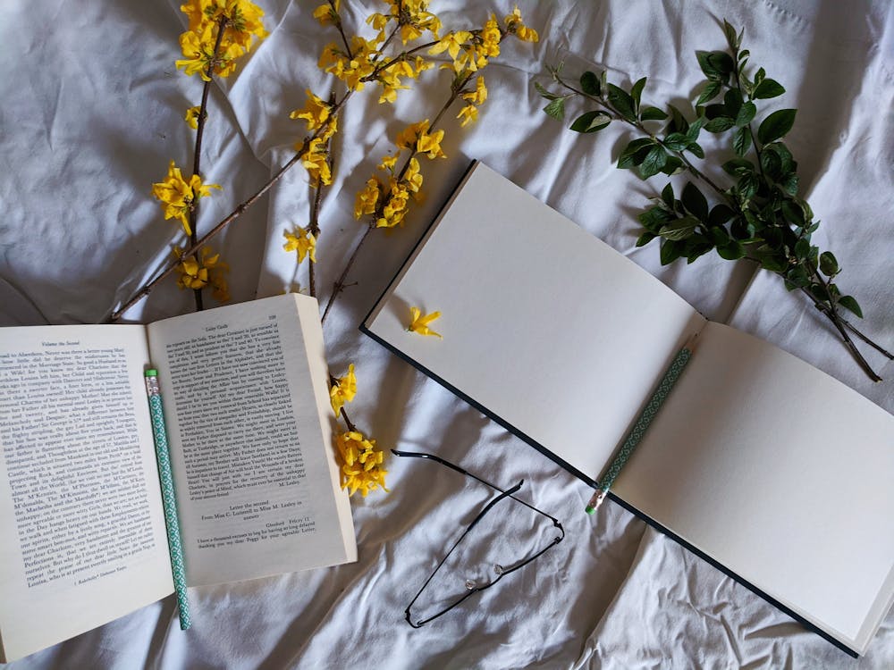 Close-Up Shot of Book and Sketchbook on White Textile