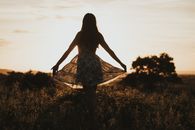 Woman in Black and White Dress Standing on Green Grass Field