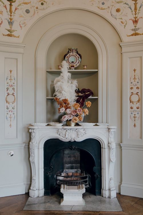 Free Ornate interior design with a classic fireplace and floral arrangement, ideal for elegant settings. Stock Photo