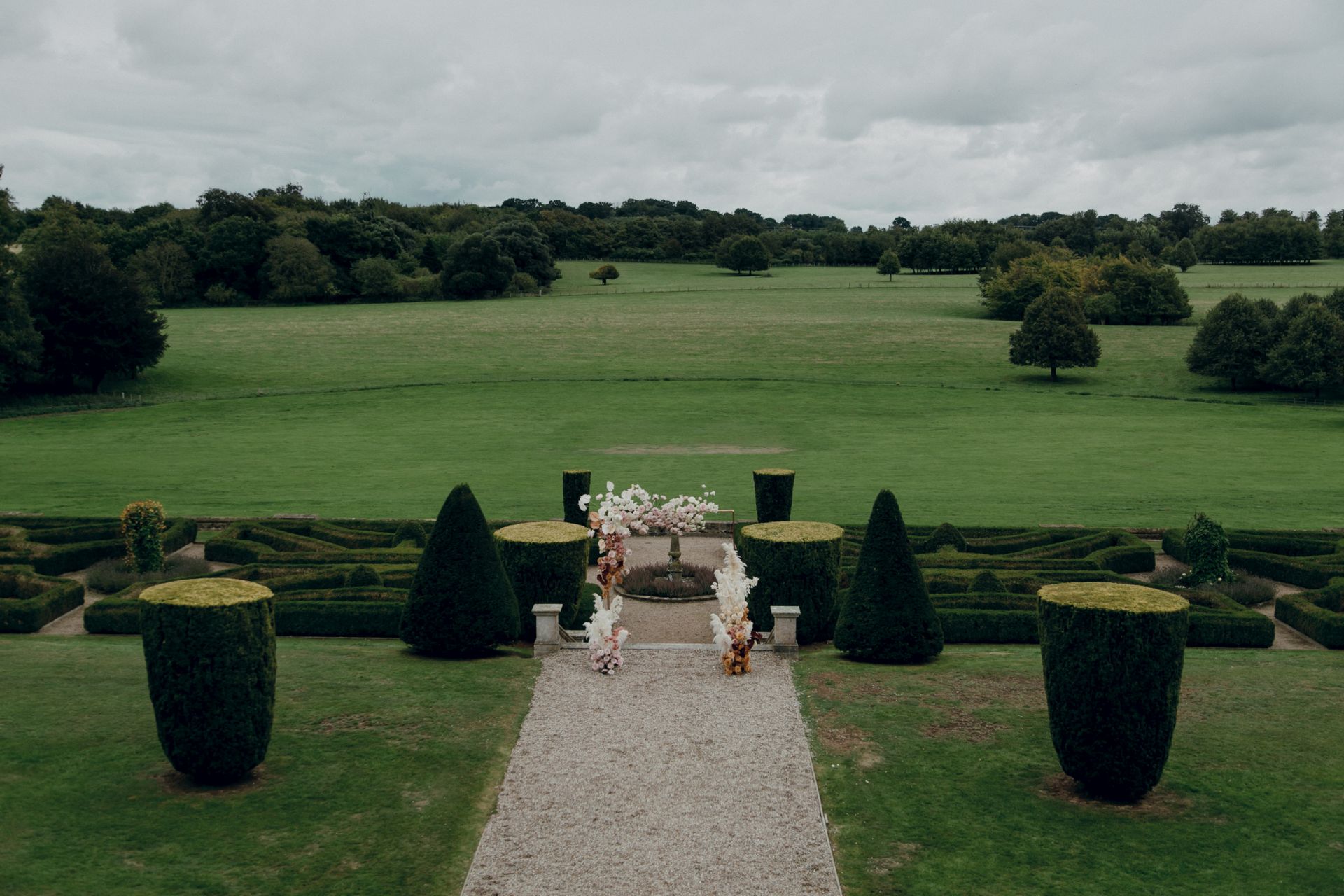 Beautiful formal garden with hedges and floral arrangements under cloudy skies.