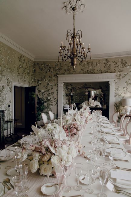 A sophisticated dining room with an exquisite table setup featuring floral arrangements and elegant decor.