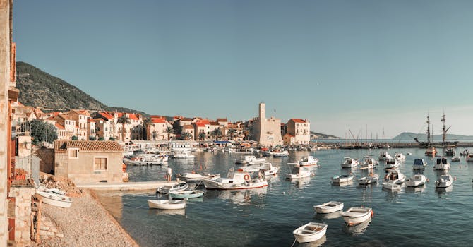 A picturesque view of Komiža harbor in Croatia with boats, historic buildings, and calm sea.
