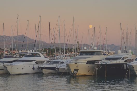 Elegant yachts docked in Split, Croatia, with a stunning sunset and mountainous backdrop.
