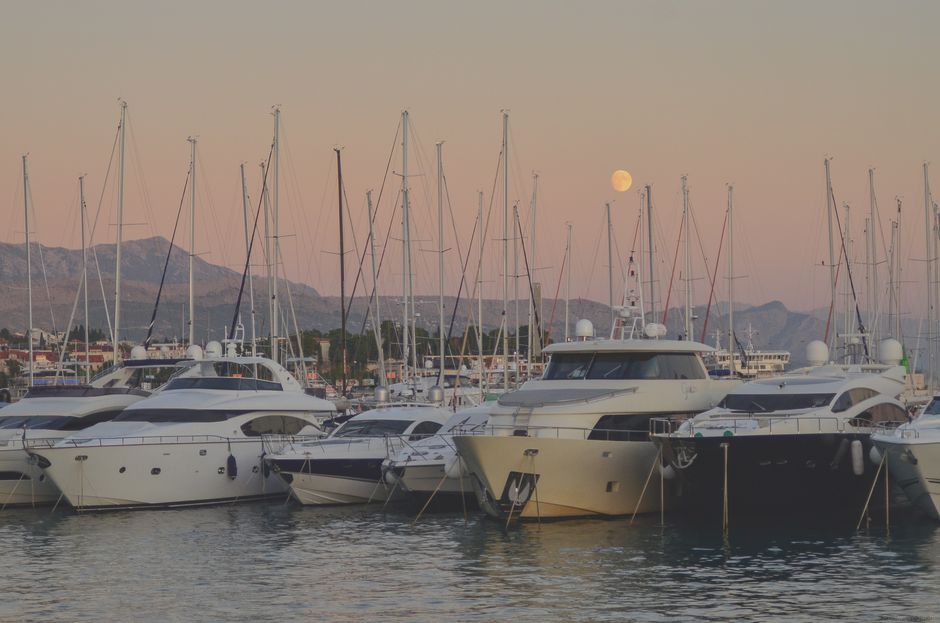 Elegant yachts docked in Split, Croatia, with a stunning sunset and mountainous backdrop.