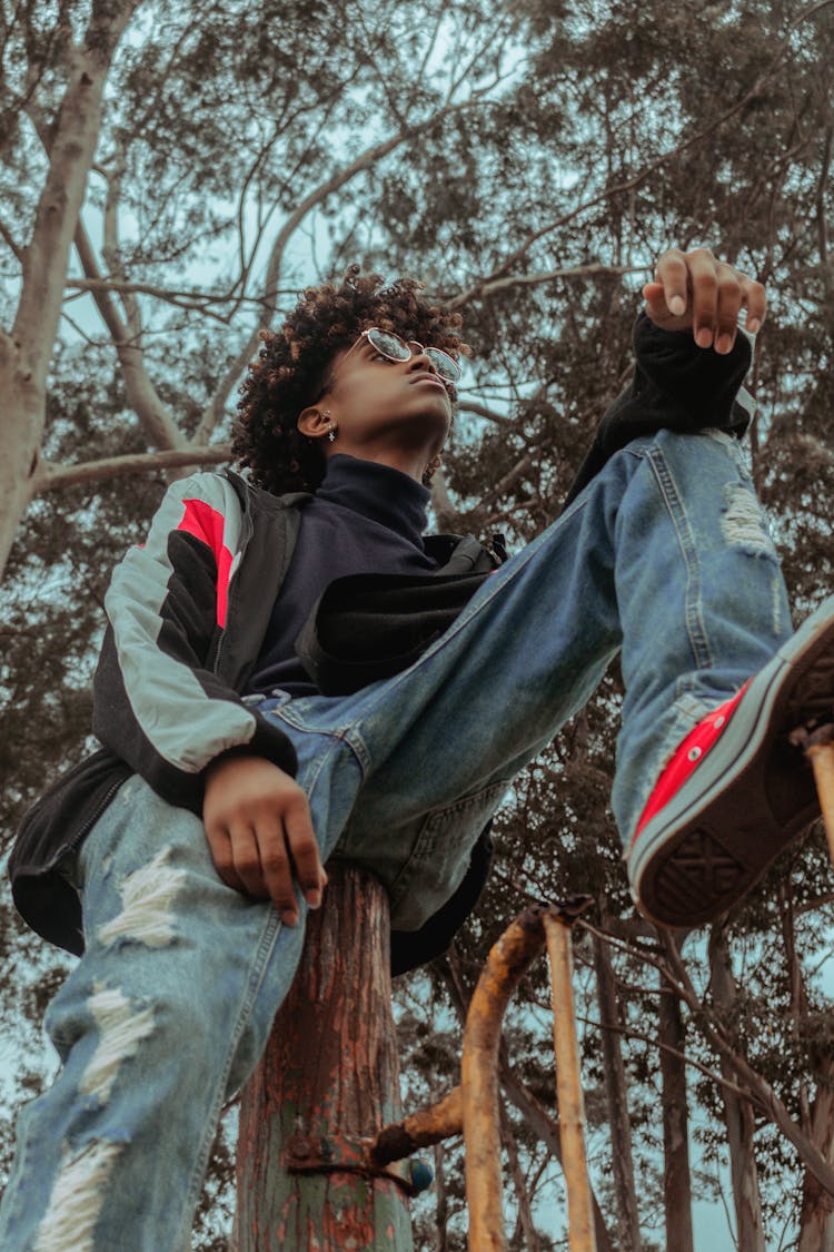 Trendy Black Hipster Man In Sunglasses Sitting On Tree Trunk