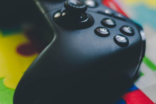Detailed close-up of a black game controller on a vibrant, colorful background.