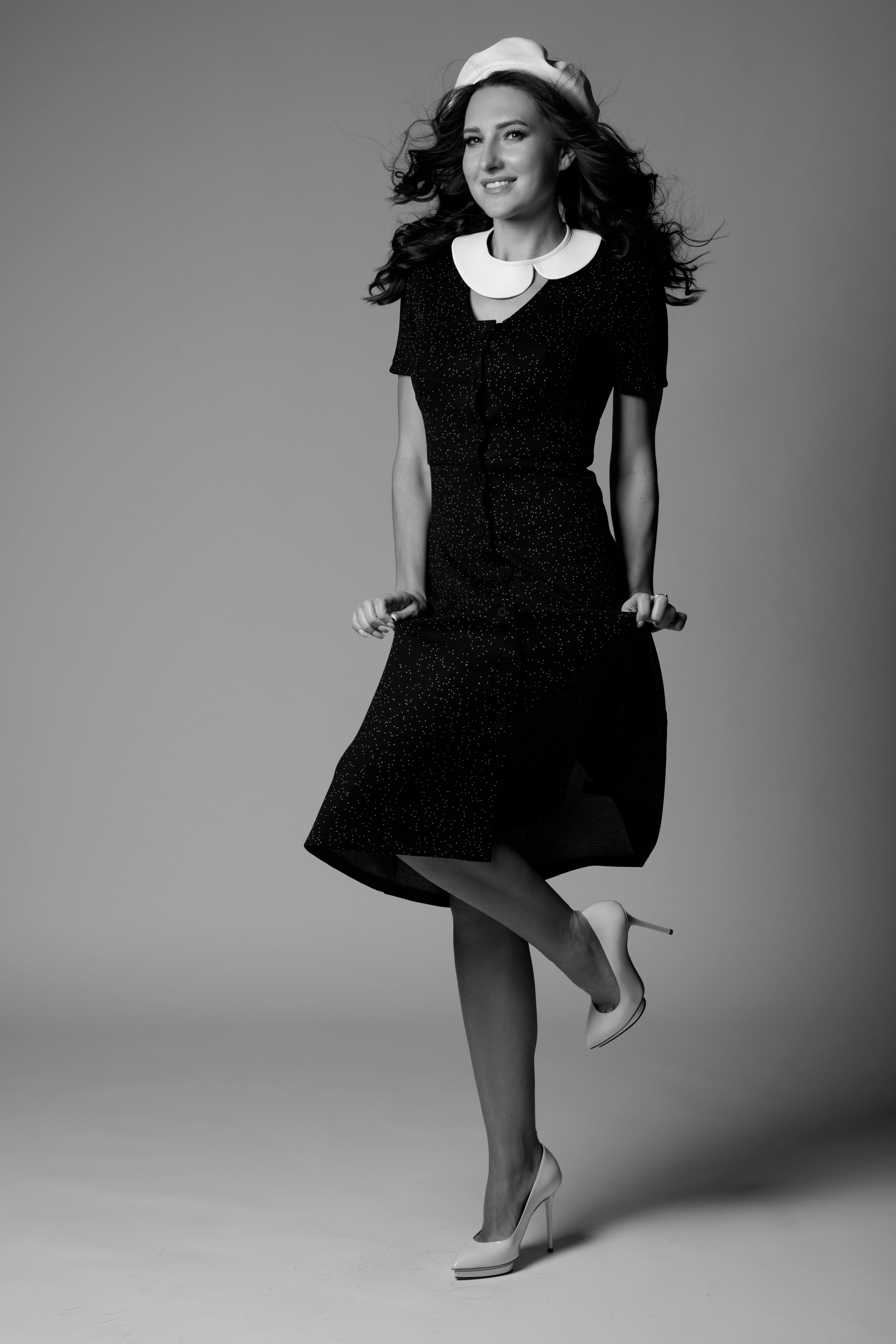 Graceful studio shot of a woman in a dress posing confidently.