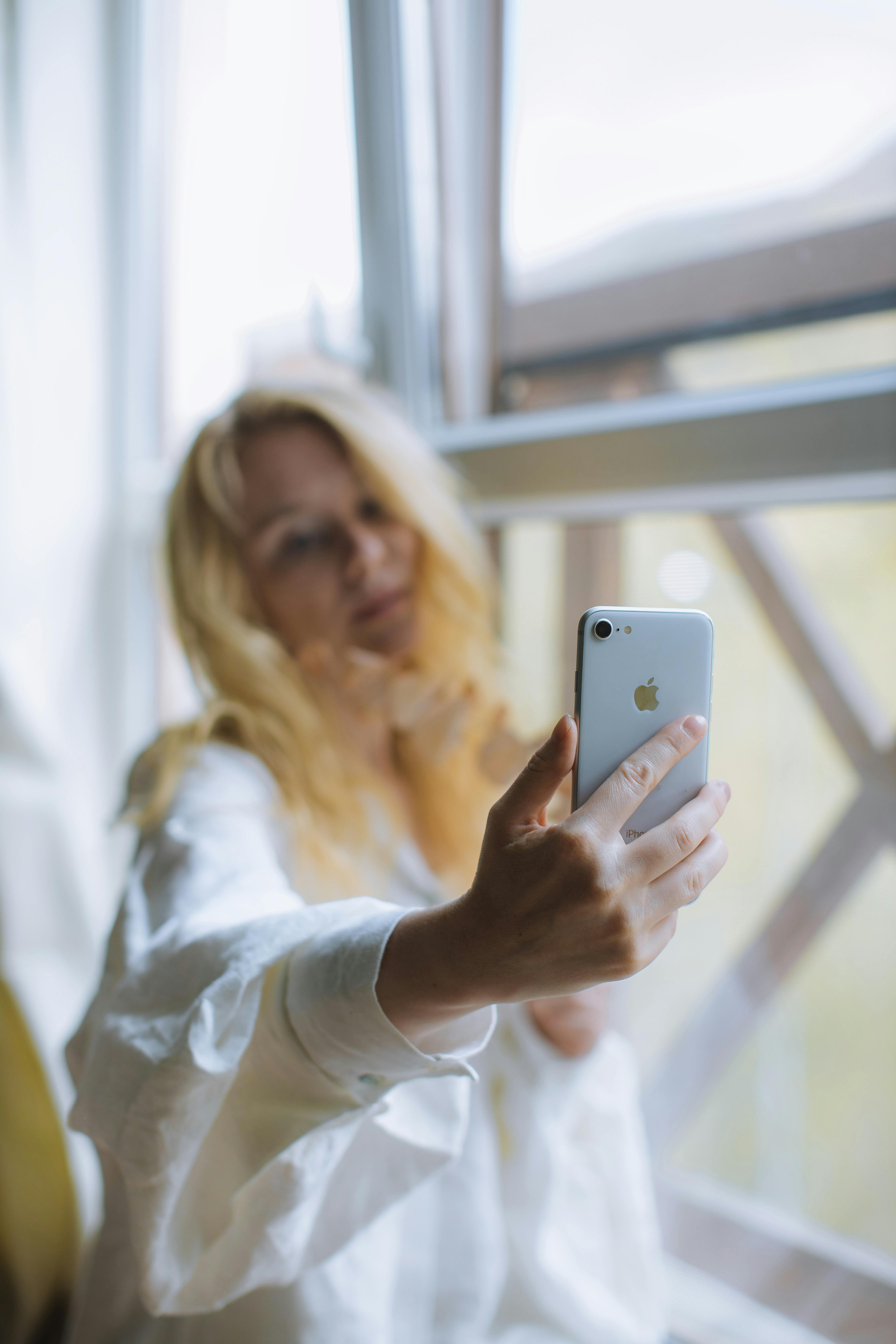 woman in white long sleeve shirt holding an iphone