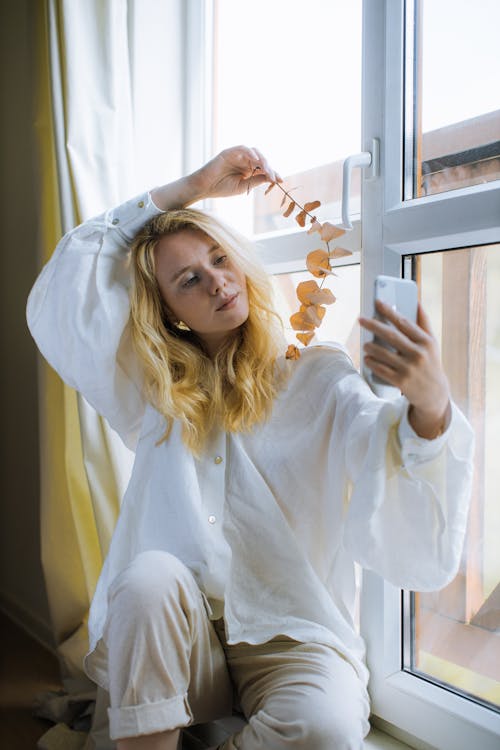 Woman in White Shirt Holding her Smartphone