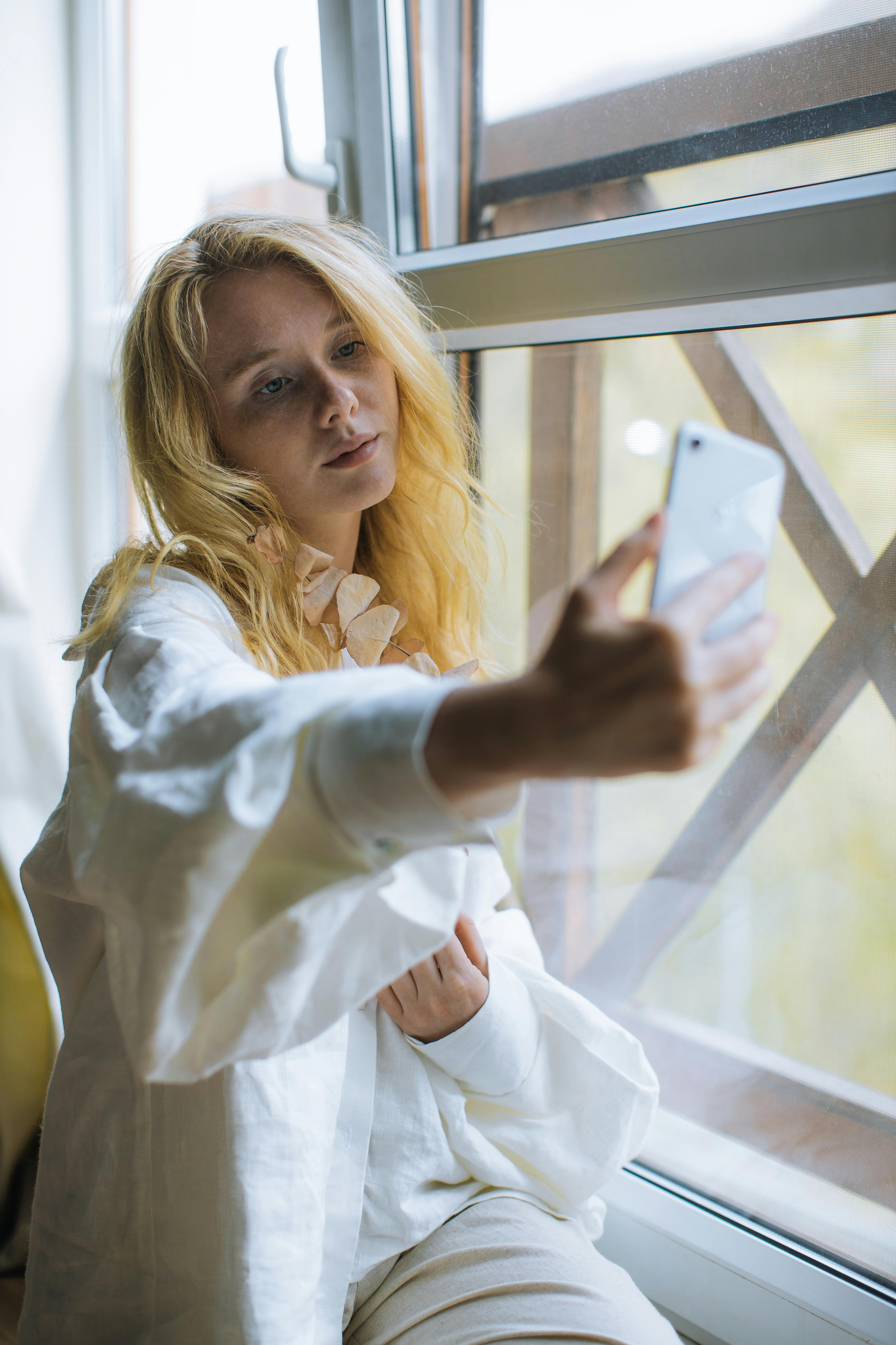 woman in white dress shirt holding iphone