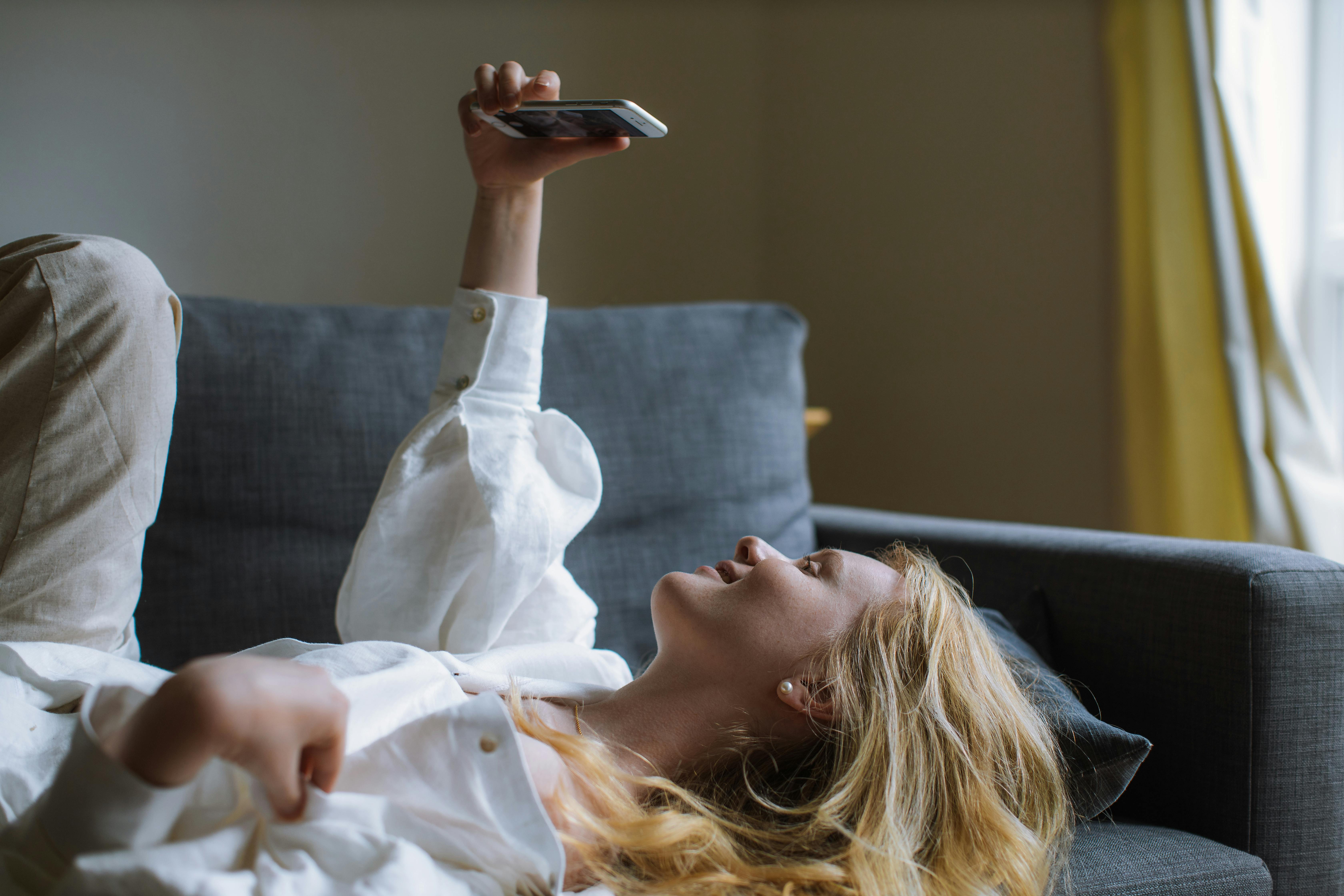 woman in white dress shirt holding a smartphone