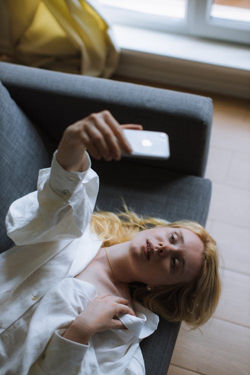 Free Woman in White Dress Shirt Lying on a Couch Stock Photo