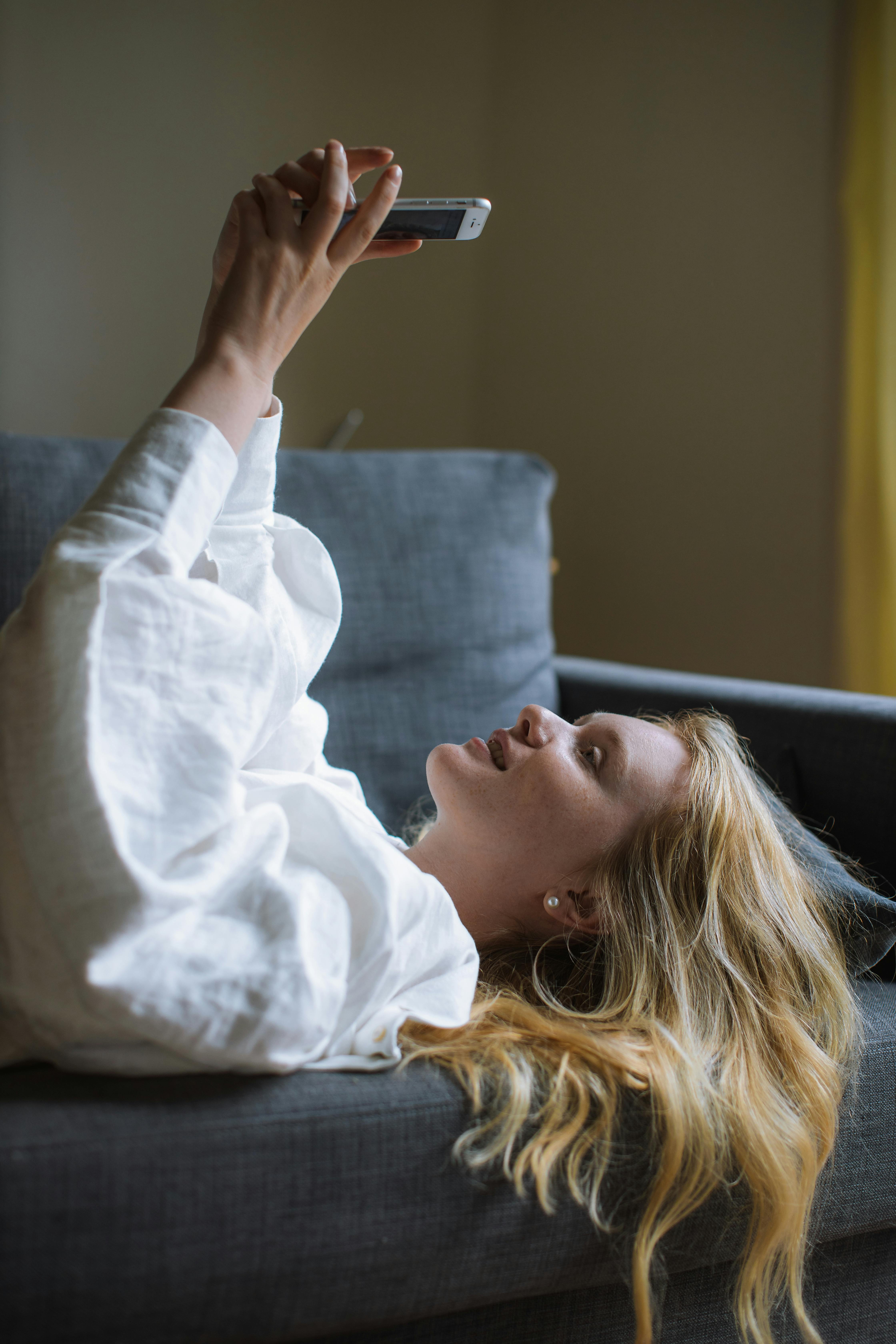 woman in white dress shirt lying on a sofa