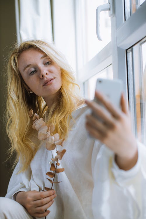 Free Woman in White Long Sleeve Shirt Holding a Smartphone Stock Photo