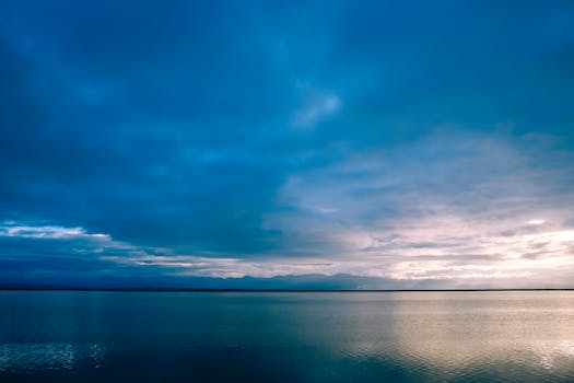 A serene ocean landscape at dusk featuring dramatic clouds and calm waters.