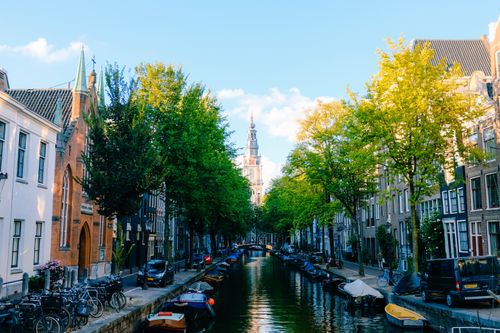 Free Perspective view of peaceful narrow canal street in Amsterdam with typical small houses on sunny spring day Stock Photo