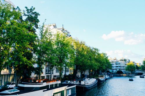 Free Perspective scenery of old city street with small residential houses located against calm canal with moored boats on clear spring day Stock Photo