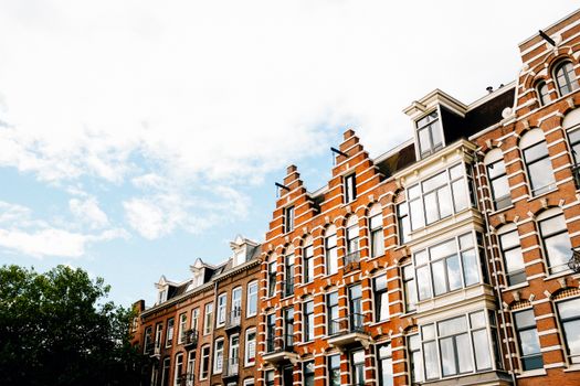 Low angle exterior of contemporary narrow apartment buildings of brown color with white decorative elements in Dutch style
