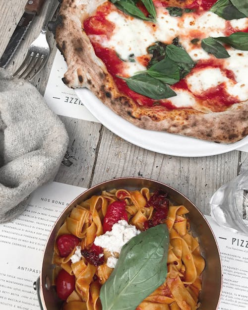 Delicious Italian pizza and pasta on restaurant table