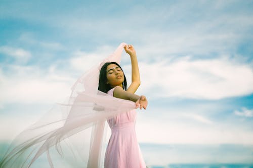 Woman in a Pink Dress Holding a Sheer Fabric