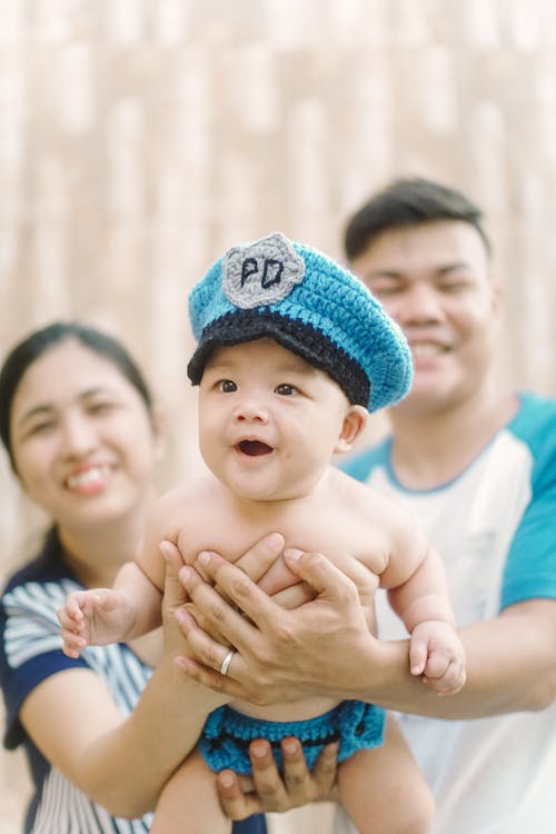 Selective Focus Photo of a Cute Baby being Carried by His Parents