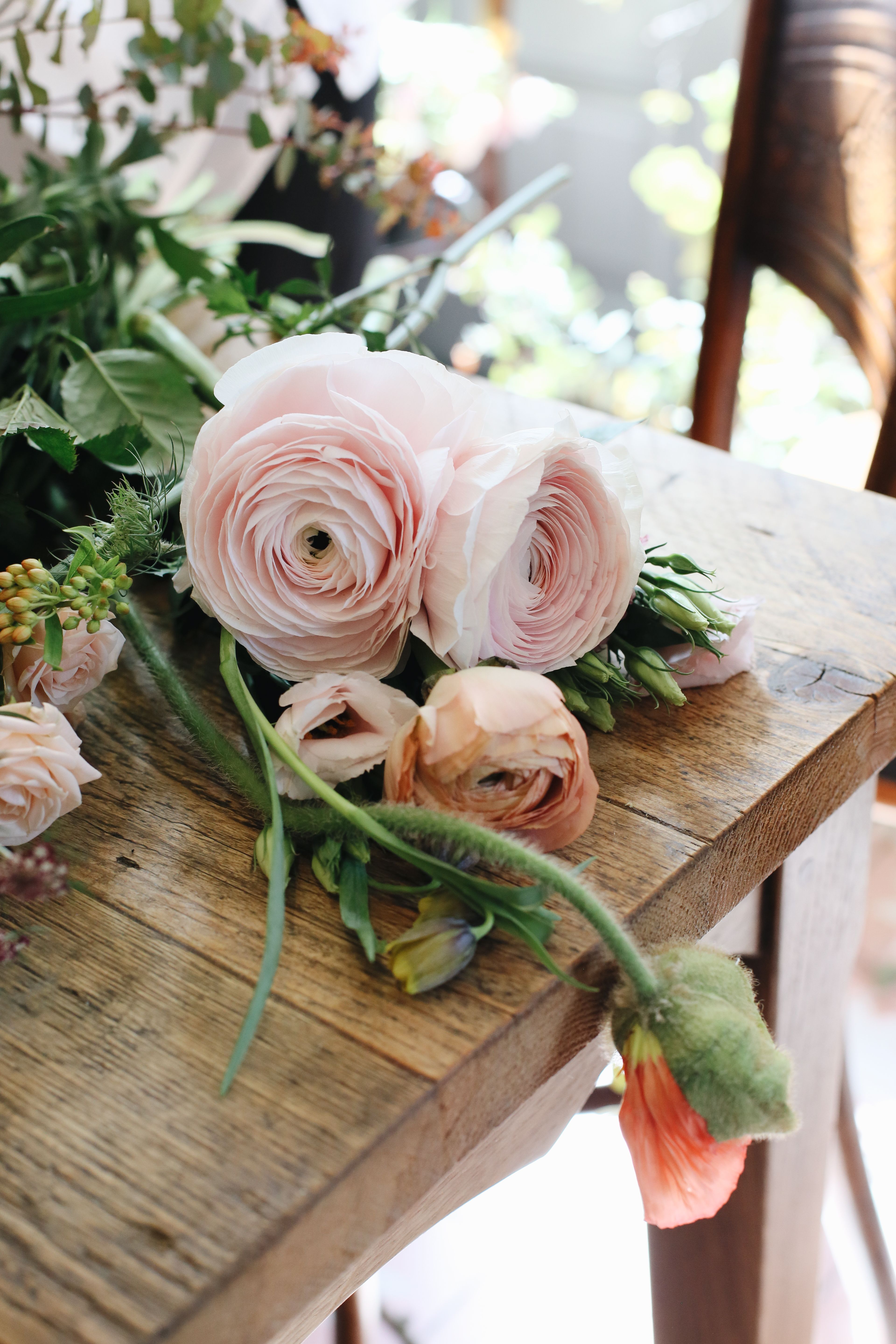 Beautiful pastel roses arranged on a rustic wooden table, showcasing delicate natural beauty.