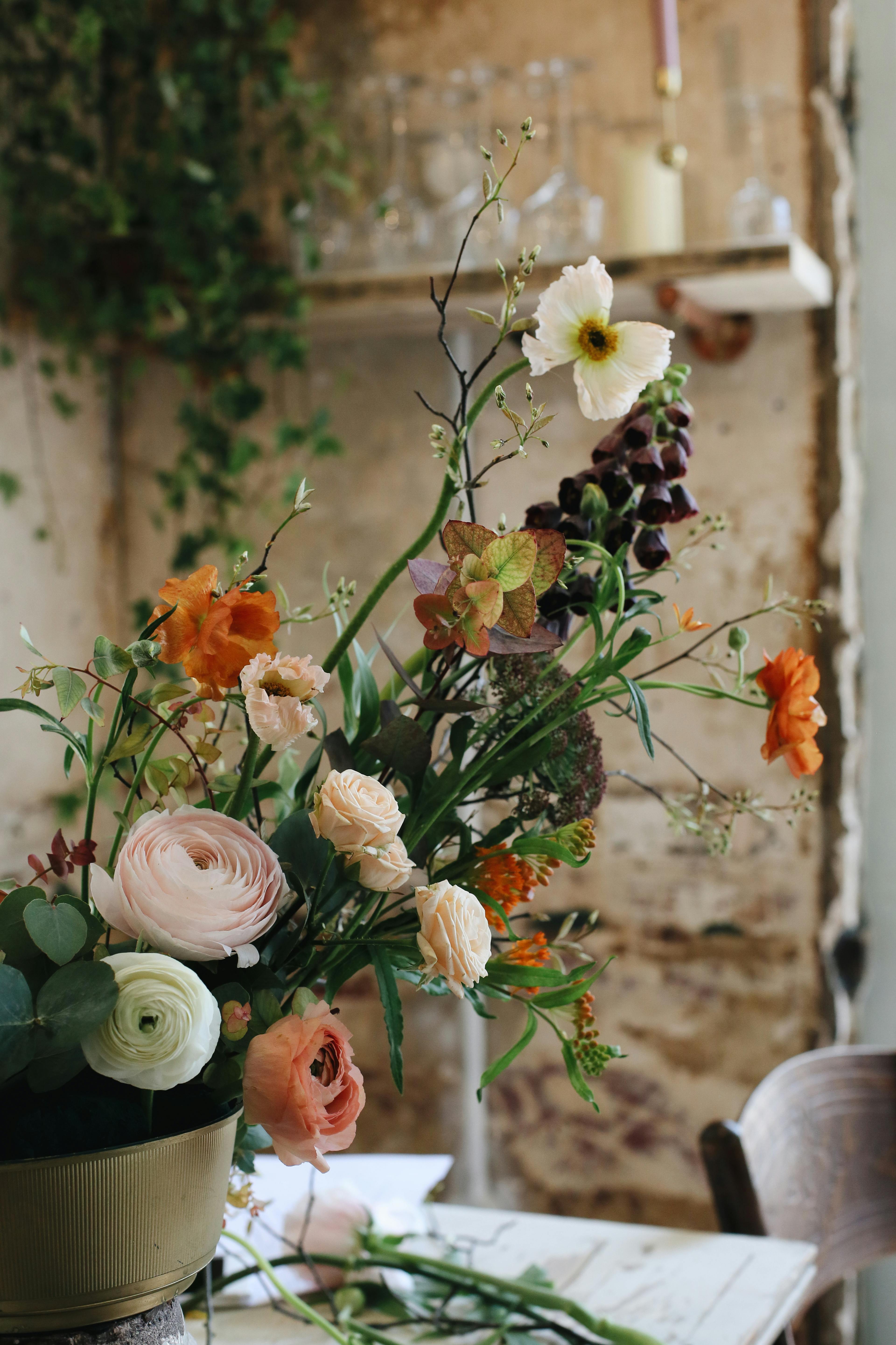 A foam-free, British-grown floral arrangement on a wooden farm table — the signature aesthetic of the British School of Sustainable Floristry