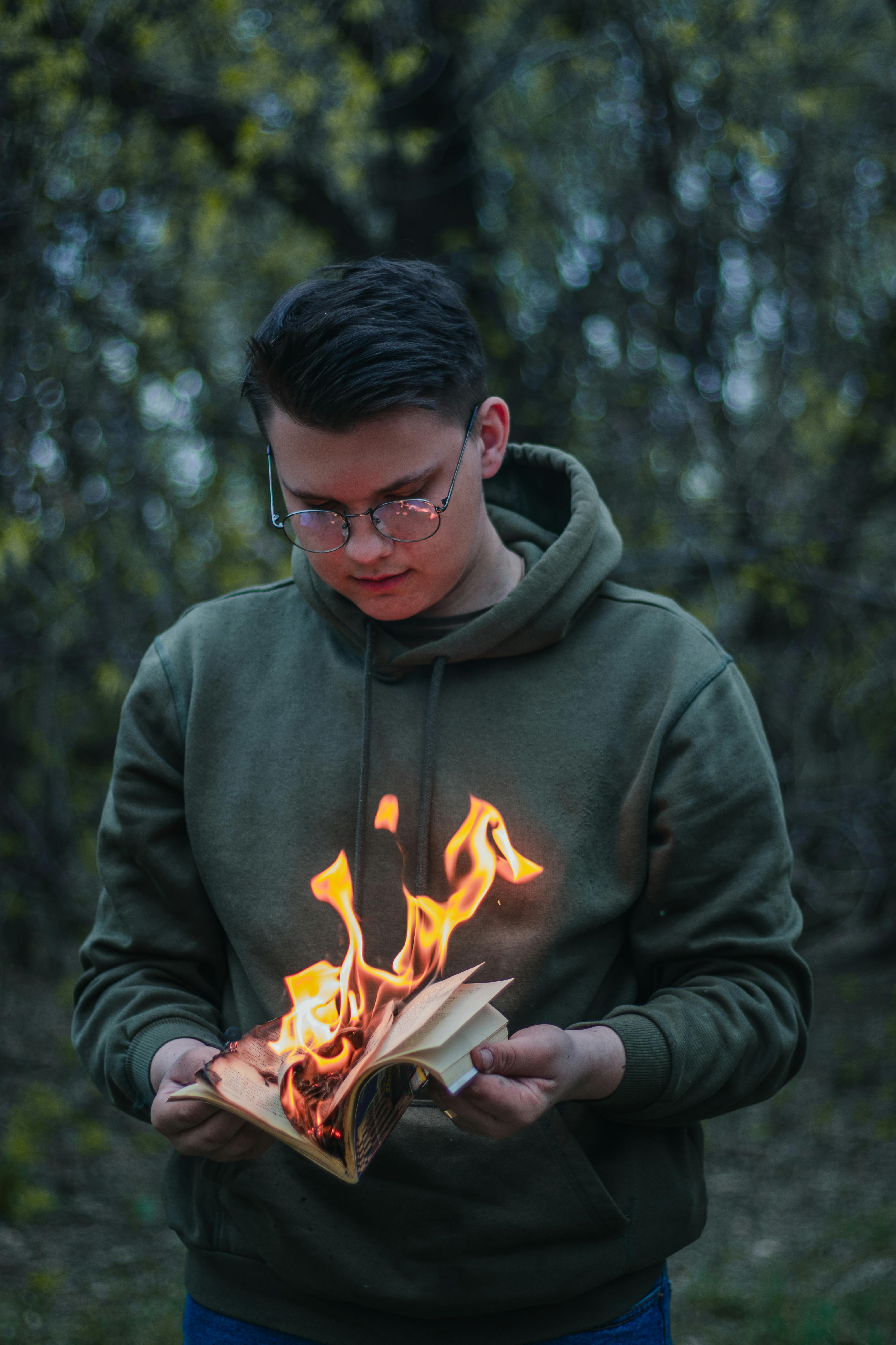 focused male teen burning diary in forest