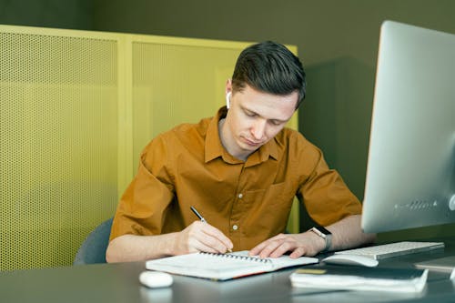 Man Taking Notes in front of his Computer