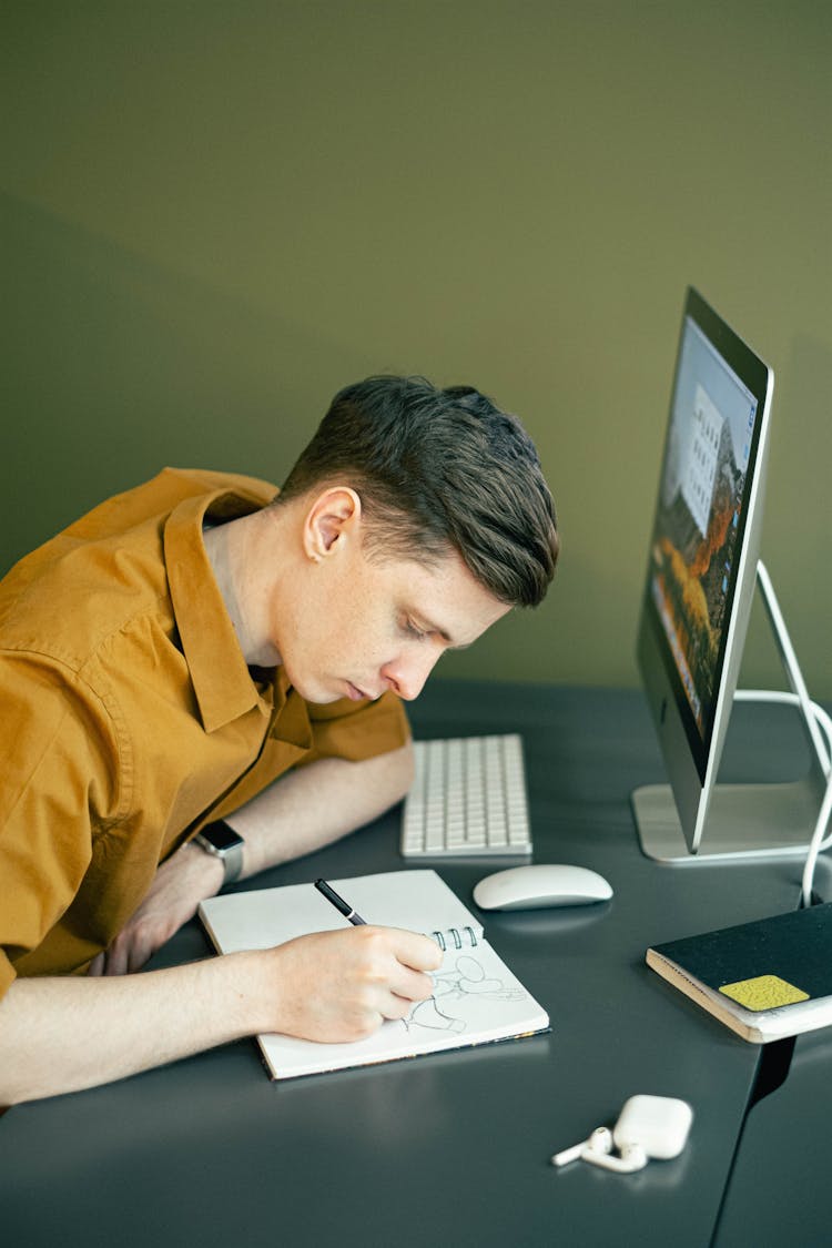 Young Man Sketching On A Notebook