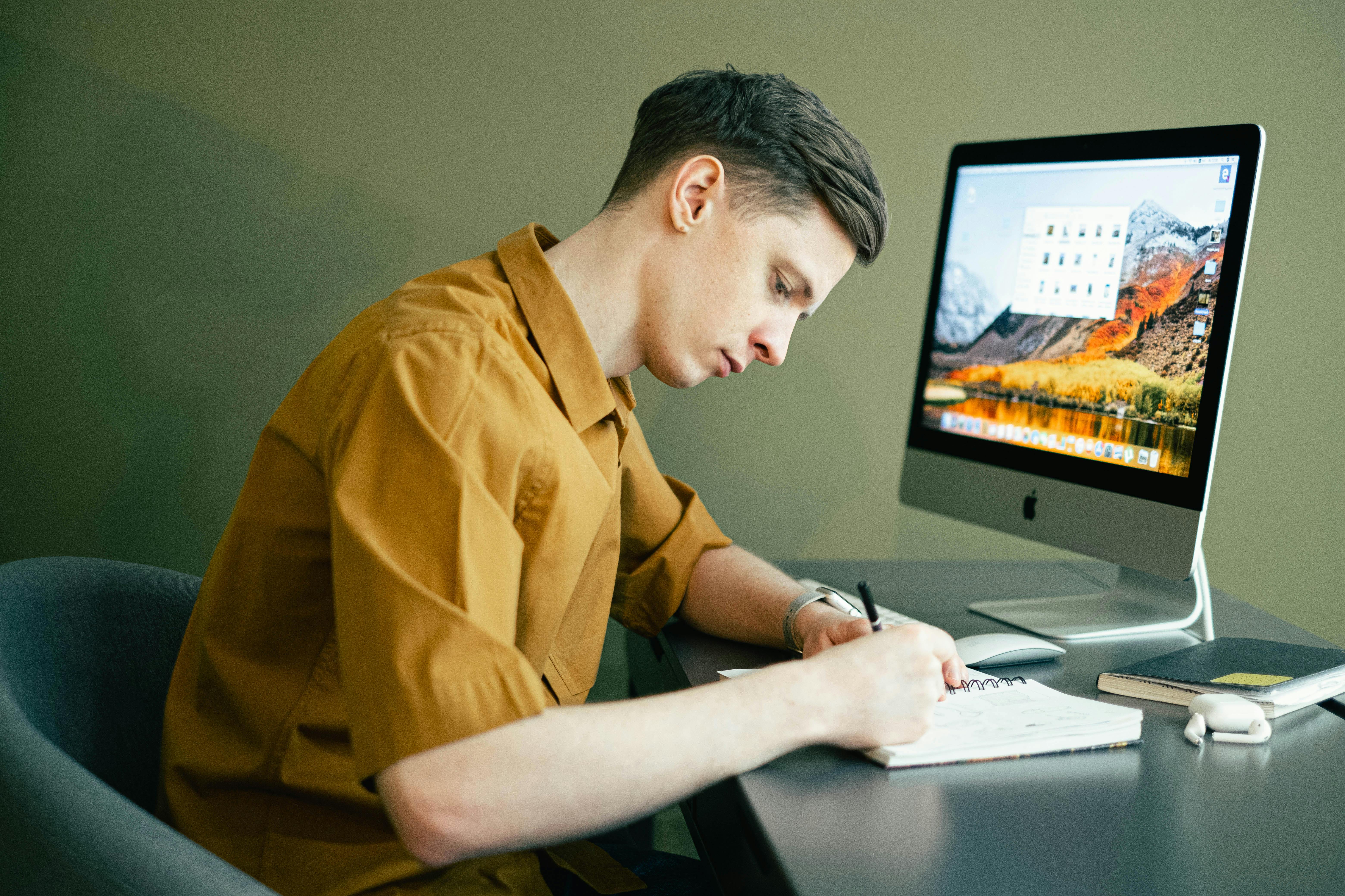 man taking notes in front of his computer