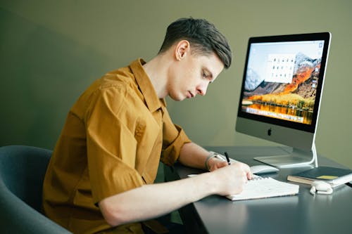Free Man Taking Notes in front of his Computer Stock Photo