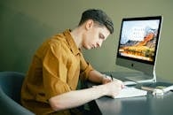 Man Taking Notes in front of his Computer