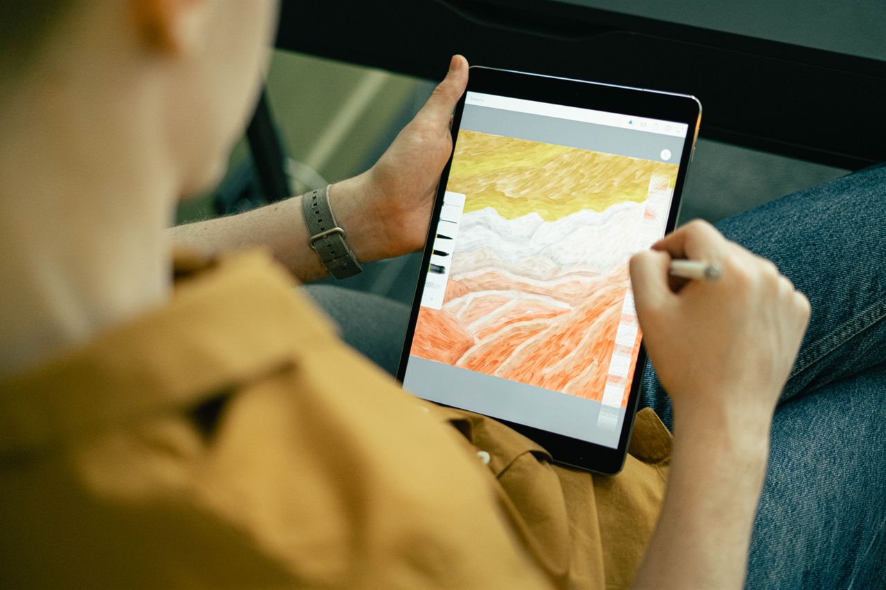 a person sketching colorful digital art on a tablet using a stylus sho