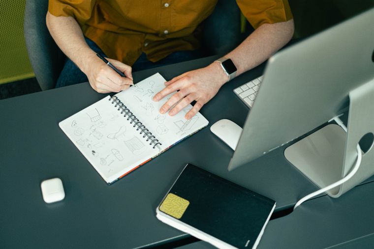 Persona dibujando en un cuaderno de bocetos en un estudio moderno