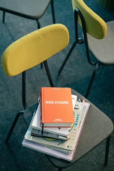 Pile of books on a modern chair, ideal for design and education themes.