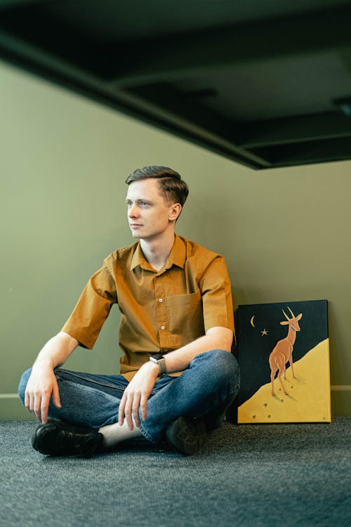 Free Man Sitting on the Floor next to a Painting Stock Photo