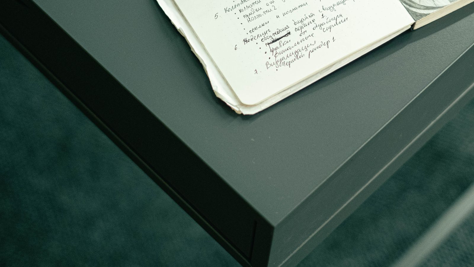 An open notebook with handwritten notes on a dark desk