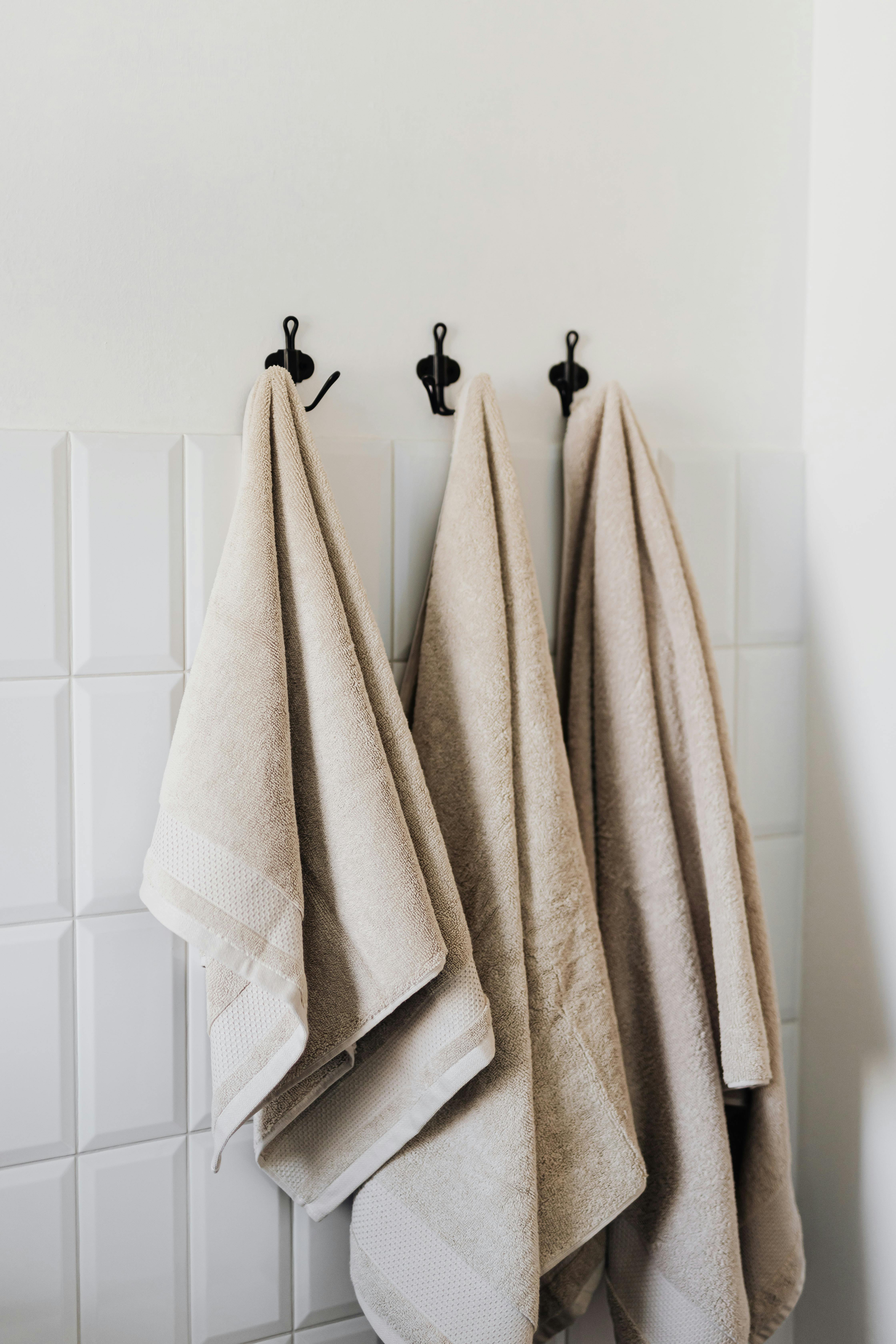 set of beige towels on hooks in bathroom