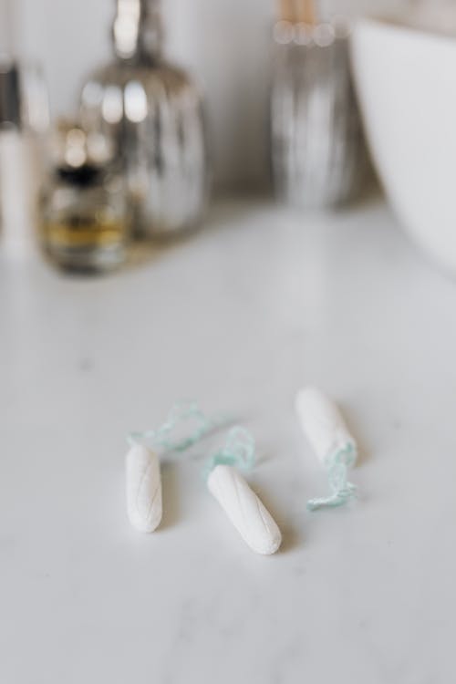 Free From above of cotton tampons placed on white marble surface near jar of perfumes and sink in modern bathroom Stock Photo