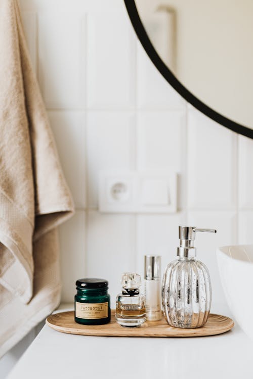 Composition of liquid soap perfume and skincare products placed on bamboo plate in modern bathroom