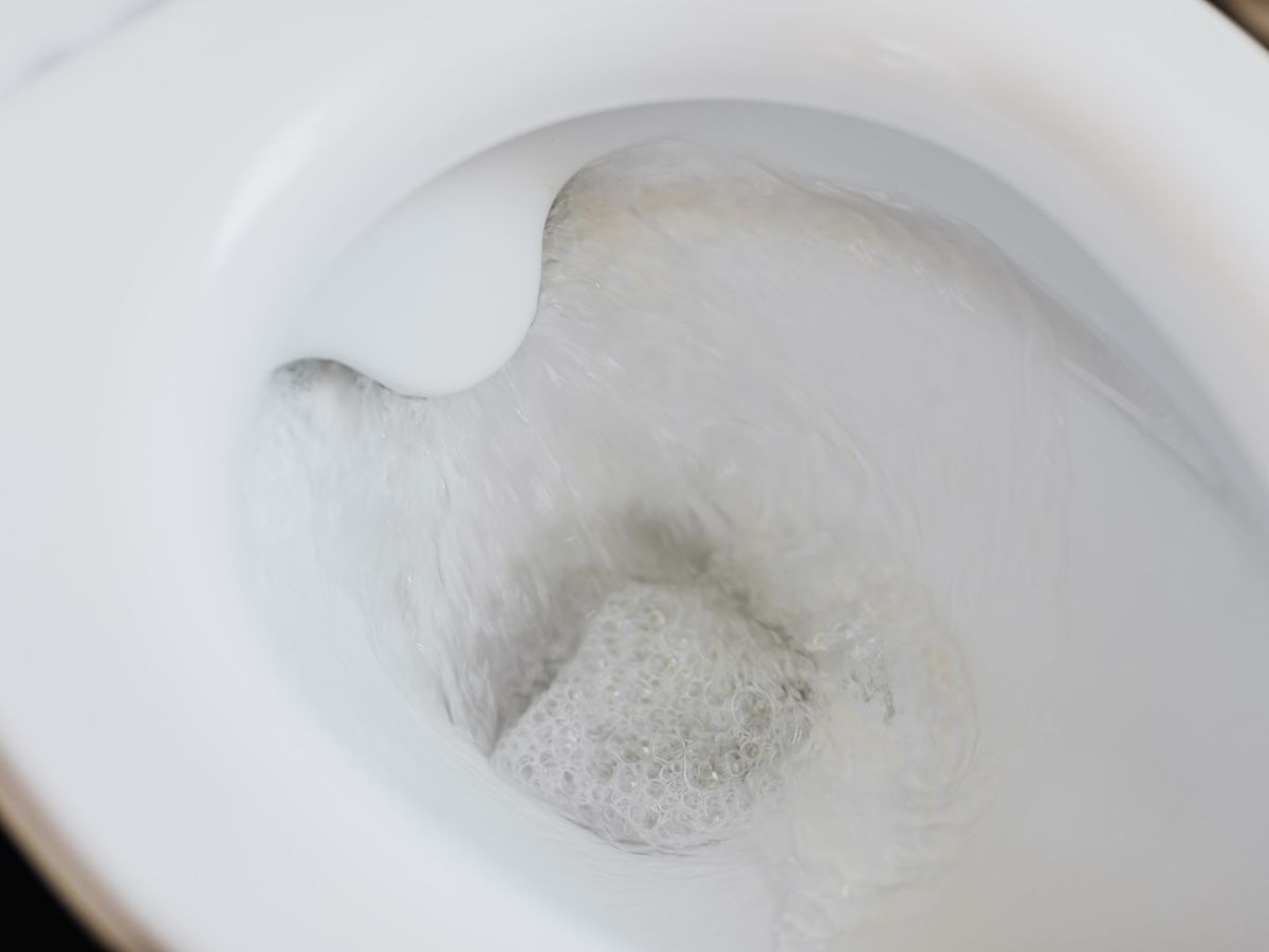 High angle of a white toilet bowl with flushing water.