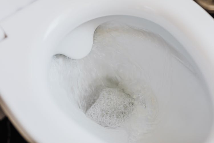 Flushing Water In White Toilet Bowl