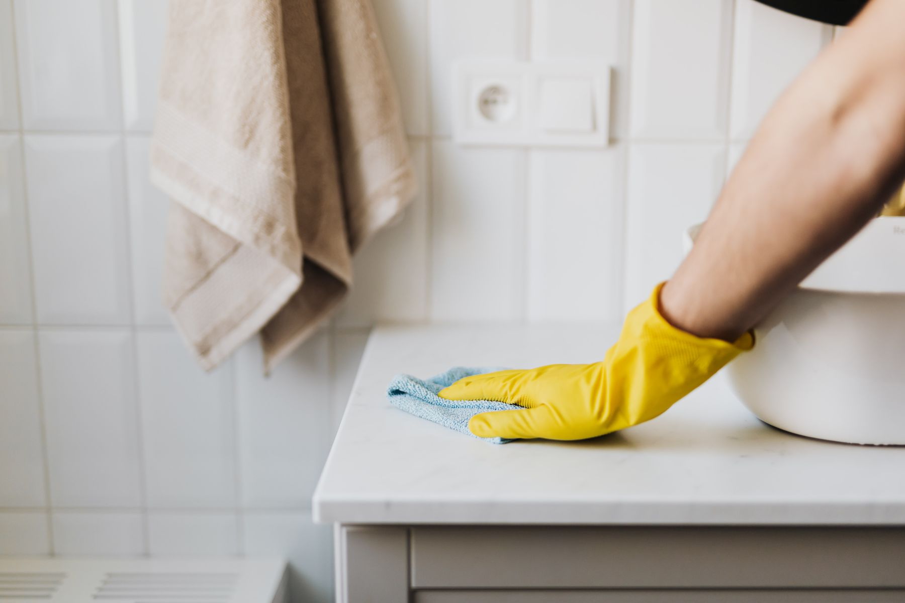 Cleaning professional wiping a bathroom vanity in a bright home