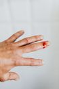 Crop unrecognizable male back hand bleeding from cut finger wound against white blurred wall